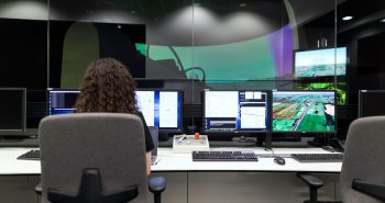 Female engineer managing multiple screens during a technology simulation in a control room.